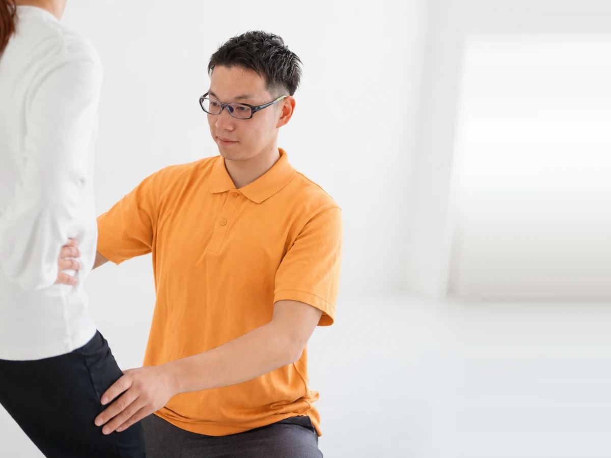姿勢を確認しながら手を添えて指導する経験豊富なトレーナー